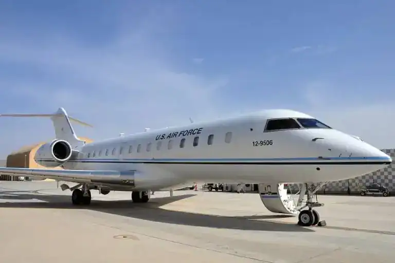 A Bombardier CRJ900 regional jet on the tarmac under a clear sky.