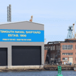 Portsmouth Naval Shipyard building with cranes and water view, promoting community support.