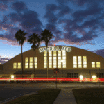 MacDill Air Force Base building illuminated at sunset with palm trees in foreground.